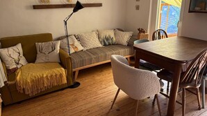 Ein gemütliches Wohnzimmer mit einer Couch, einem Esstisch und einer Lampe.