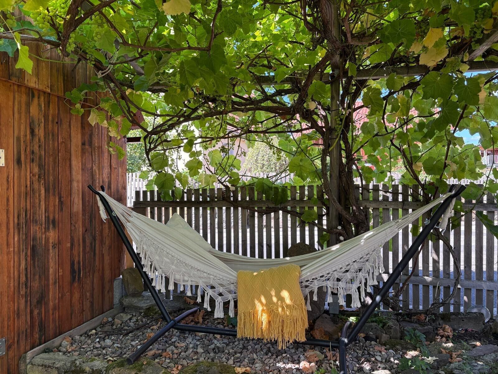 Un'amaca sotto un albero con un recinto di legno sullo sfondo.