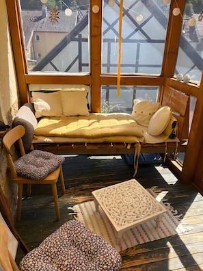 Um quarto de madeira com uma cama, uma cadeira e uma pequena mesa.