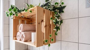 Een houten plank met opgerolde handdoeken en groene planten.