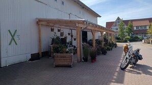 Een gebouw met een houten pergola, plantenbakken en een motorfiets voor de deur.