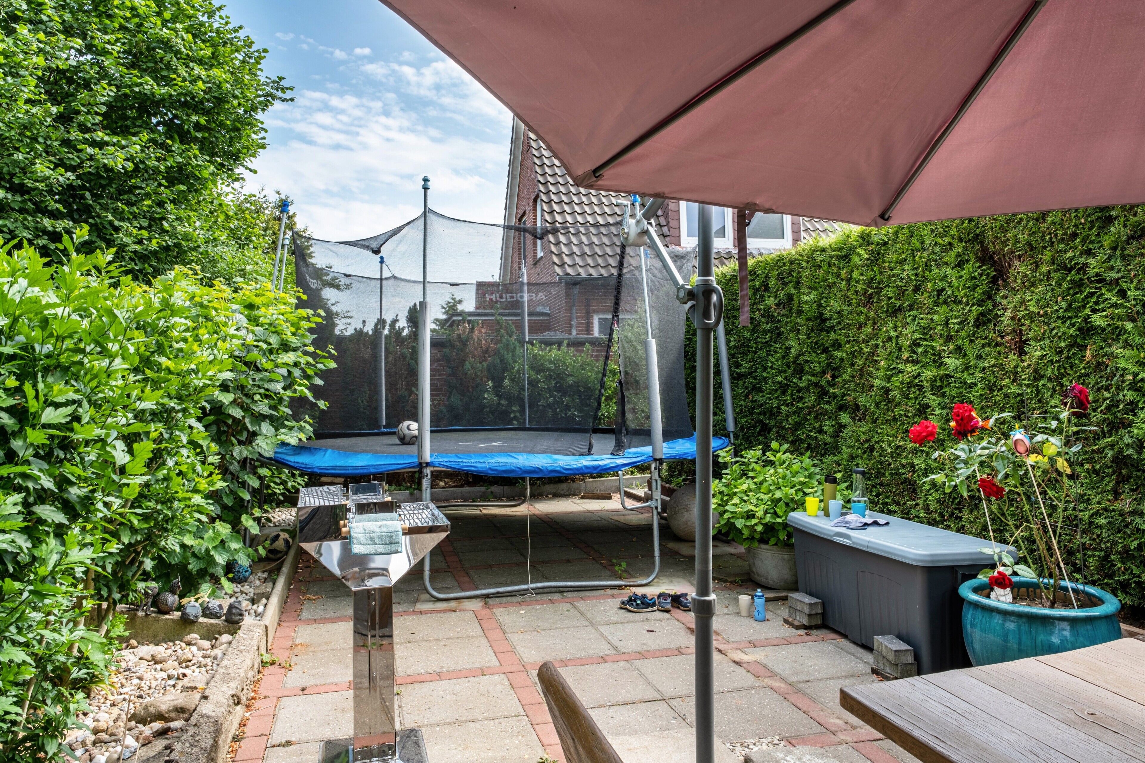 Un jardin avec un trampoline, une table et un pot de fleurs.