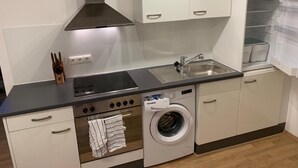 A compact kitchen with a stove, oven, washing machine, and a sink.