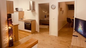 Un appartement moderne comprenant une cuisine, un coin repas et un salon avec télévision.