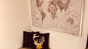 A small seating area with a world map, a fur throw, and a pillow with a deer head design. - Holiday Apartment "Felix Living 2" with Wi-Fi (Passau)