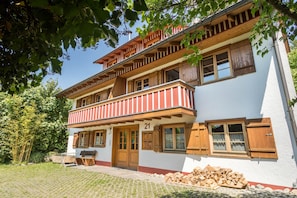 Un immeuble de deux étages doté d’un balcon, de volets en bois et d’une enseigne portant le numéro 21.