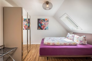 Ein Schlafzimmer mit einem Bett, einer Deckenleuchte, einem Fenster und einem Bild an der Wand.