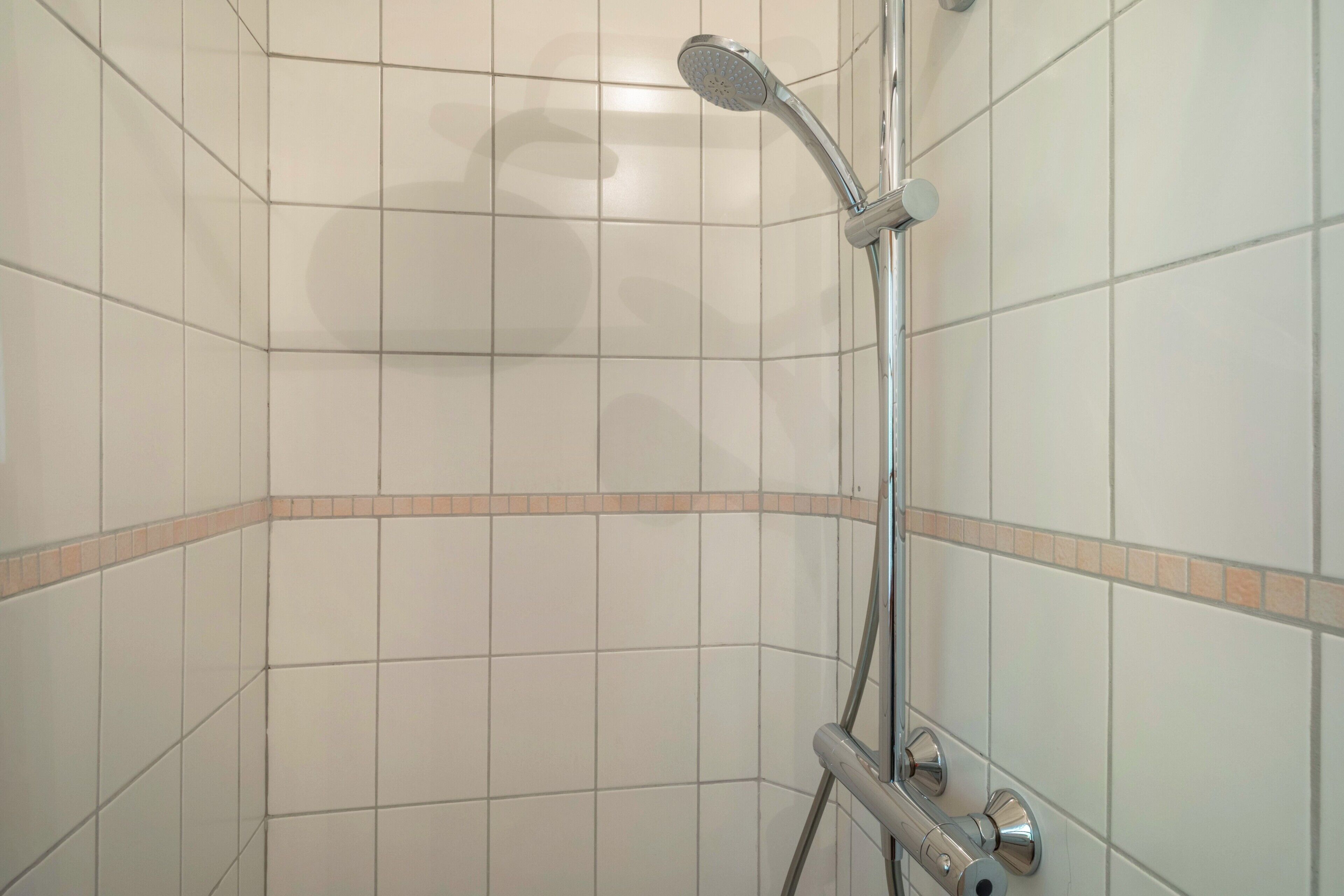 Eine Dusche mit Handbrause und Armaturen an der Wand.