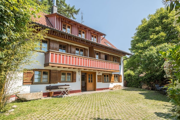 Ein zweistöckiges Gebäude mit Balkon, Holztür und Hausnummer 21.