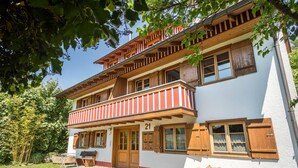 Un immeuble de deux étages doté d’un balcon, de volets en bois et d’une enseigne portant le numéro 21.