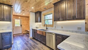 A modern kitchen with wooden cabinets, stainless steel appliances, and a marble countertop. - Cozy & Peaceful Waterfront Cabin on Porter Lake! (New Vineyard)