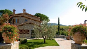 A stone building with a tiled roof, surrounded by a well-maintained garden with potted plants and a clear pathway leading to the entrance. - Lamore di Carla by Interhome (Greve in Chianti)
