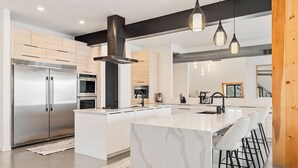 Una cocina moderna con una isla grande, electrodomésticos de acero inoxidable y una zona de bar.