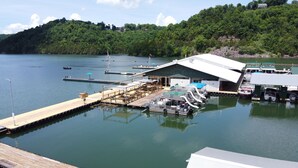 Un barco amarrado con una zona de estar cubierta y un edificio que dice 'SUNSET DOCK'.