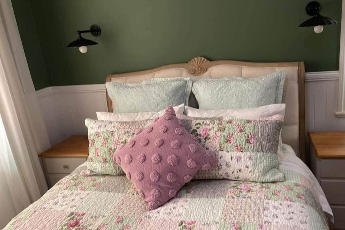 A bed with floral bedding, two pillows, and a wooden headboard.