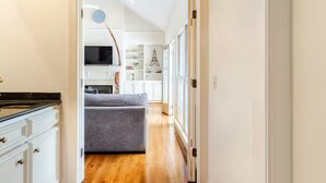 A narrow hallway with a grey sofa, white cabinets, and a wooden floor. - 5000Sqft MassiveHome,5.5Bath,Pool,HotTub,Mins to CopperCreekTennis, Fort-Benning (Columbus)