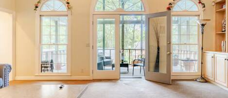Un'ampia stanza con un grande tavolo, due finestre ad arco con porte in vetro e vista sull'esterno.