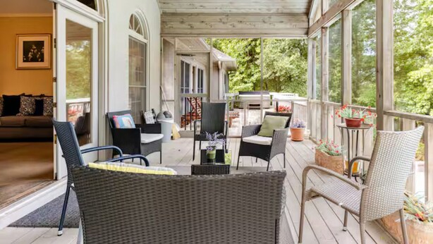 A covered porch with wicker furniture, a dining table, and potted plants. - 5000Sqft MassiveHome,5.5Bath,Pool,HotTub,Mins to CopperCreekTennis, Fort-Benning (Columbus)