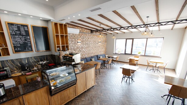 Un café moderno con pared de ladrillo, mobiliario de madera y suelo de espiga.