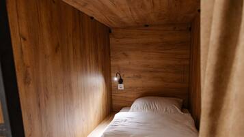 Una piccola camera con un letto singolo, pareti in legno e un arredamento semplice e funzionale.