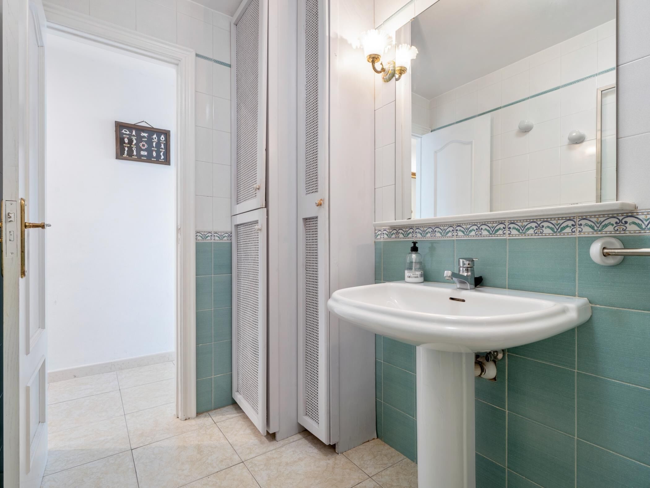 Un baño con lavamanos blanco, un espejo y una ducha.