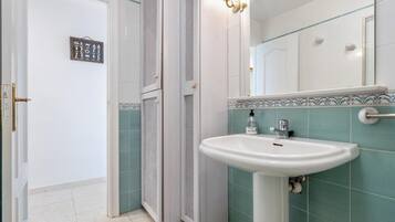 Un baño con lavamanos blanco, un espejo y una ducha.