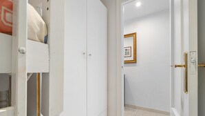 Ein heller Raum mit einem Kleiderschrank, einer Tür mit Messinggriffen und einem gerahmten Bild an der Wand.