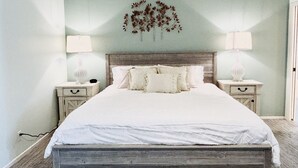 Ein Schlafzimmer mit einem Bett, zwei Nachttischen und einer Wanddekoration.