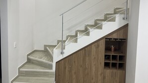 Een trap met een houten afwerking en metalen leuning, die naar een lager gelegen niveau leidt.