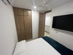 Ett sovrum med en säng, en garderob, en takfläkt och en tv som är monterad på väggen.