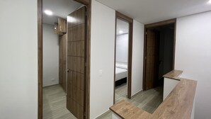 Een gang met een houten kast, een bed en een spiegel.