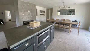 A spacious kitchen with a large island, built-in oven, and a dining area with a wooden table and chairs. - Oceanside Gem W/ Pool, Hot Tub and Game Room! (Oceanside)