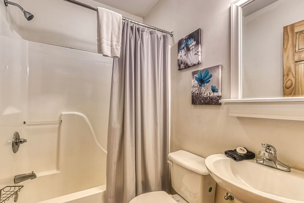 Une salle de bain avec une baignoire, des toilettes et un lavabo. Deux tableaux encadrés sont accrochés au mur.