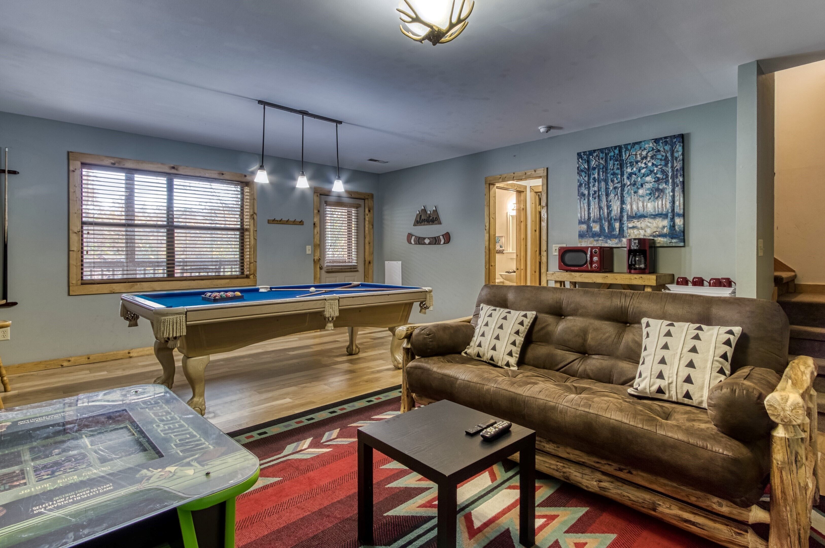 A cozy living room with a pool table, a leather sofa, and a coffee table.