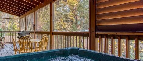 A hot tub on a wooden deck with a view of trees.