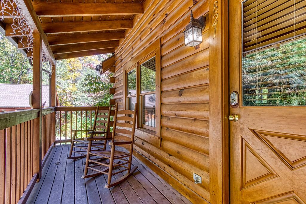 A wooden cabin with a porch, rocking chairs, and a door with a number.
