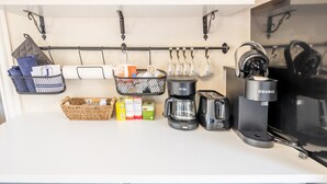 Una cucina con macchina da caffè, tostapane e forno a microonde. Sul bancone ci sono cesti e contenitori.