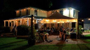 Un'area patio all'aperto con tavoli, sedie, una tenda e un palco per musica dal vivo.