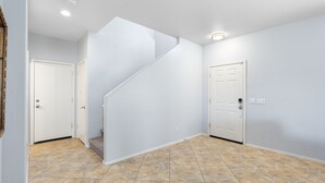 Ein sauberes, modernes Treppenhaus mit Fliesenboden, weißen Wänden und einer Treppe, die zu einem anderen Raum führt.