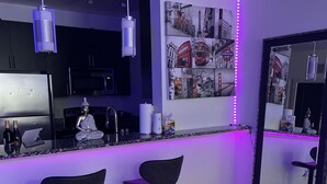 Cocina moderna con barra, dos taburetes y un espejo grande.