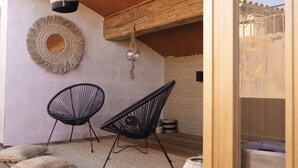 A room with two black wireframe chairs, a woven wall hanging, and a hanging glass ornament. - Ennéa - Jacuzzi & Luxury Suites (Perpignan)