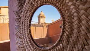 A view through a woven circular frame, focusing on a building with a tower and a flag. - Ennéa - Jacuzzi & Luxury Suites (Perpignan)