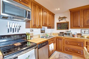 Una cocina con armarios de madera, electrodomésticos de acero inoxidable y un menú en pizarra.