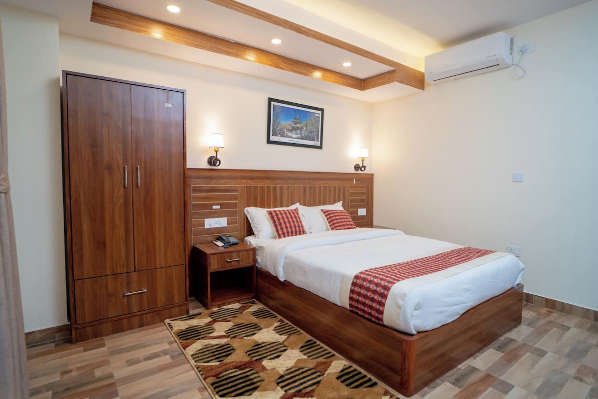 A bedroom with a wooden bed, nightstands, a wardrobe, and a patterned rug.