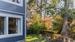A residential property with a modern house, a well-maintained garden, and a natural setting with trees and shrubs.