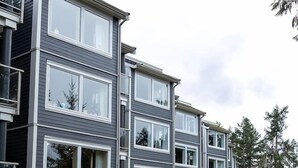A multi-story residential building with a modern design, featuring large windows and a well-maintained lawn.