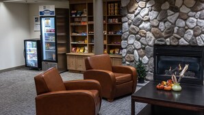 A lobby with leather chairs, a stone wall, a fireplace, a snack bar, and a vending machine.
