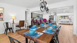 Een eetgedeelte met een houten tafel voor vier personen, blauwe kommen en een fiets aan het plafond.