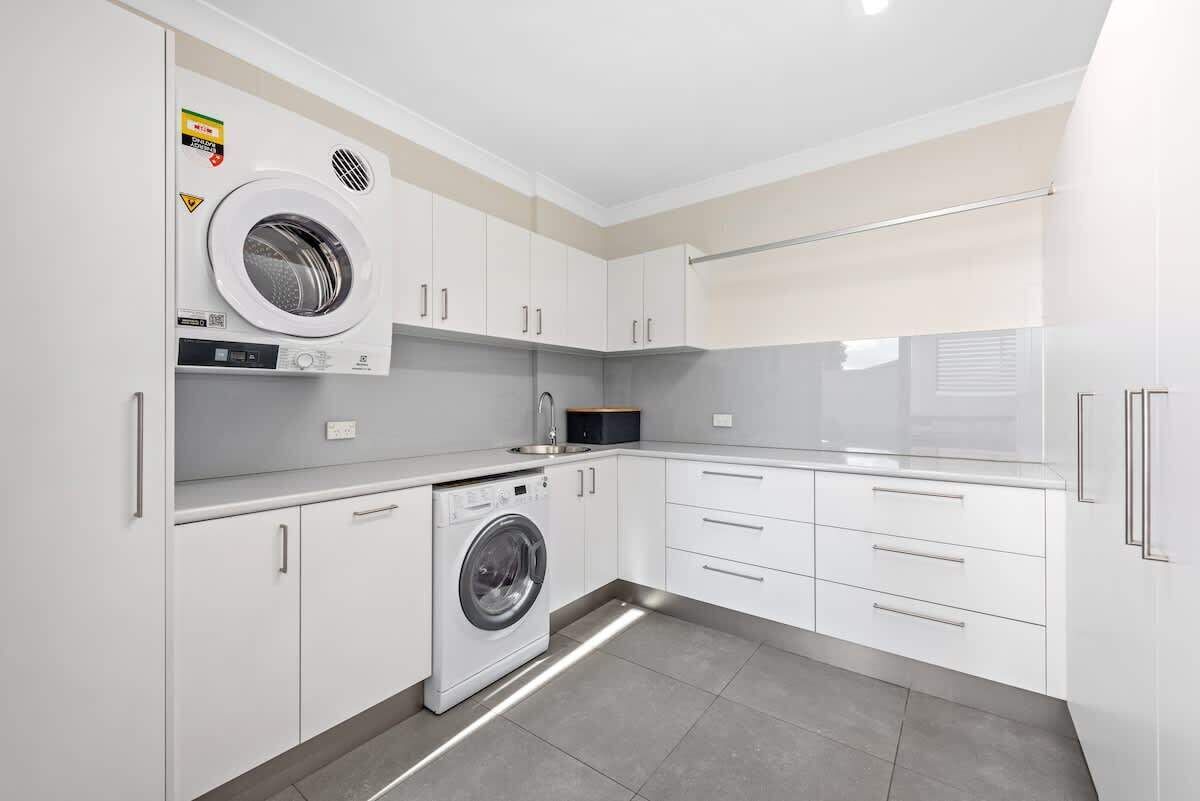 A compact kitchen with a built-in washer and dryer, white cabinetry, and a small countertop.