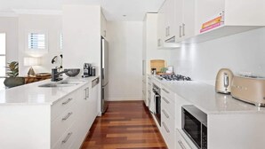 Una cocina moderna con armarios blancos, una isla central, horno empotrado y microondas.